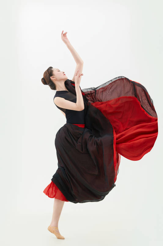 身穿红黑相间的舞蹈长裙翩翩起舞的少女图片