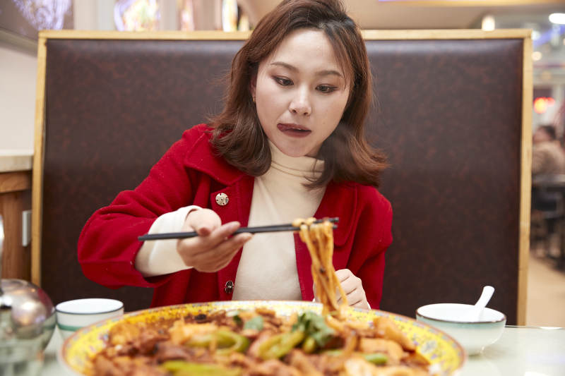 在餐厅吃美味新疆大盘鸡的亚洲少女图片