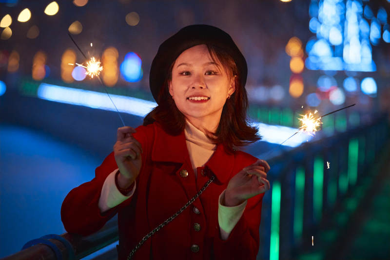 夜晚燃放仙女棒的可爱亚洲少女图片