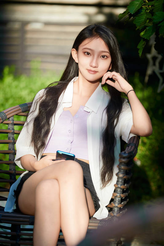 夕阳下在庭院休息拍照的亚洲少女图片