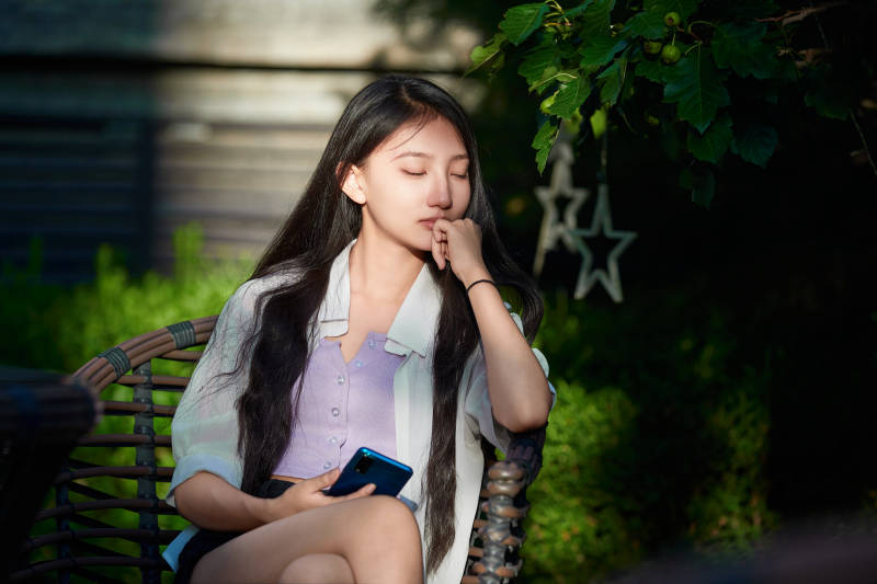 夕阳下在庭院休息拍照的亚洲少女图片