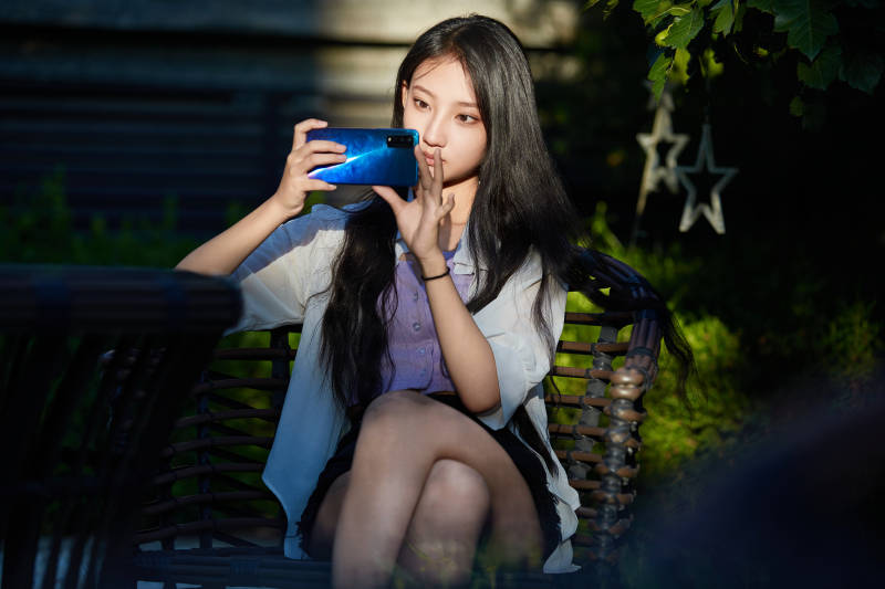 夕阳下在庭院休息拍照的亚洲少女图片