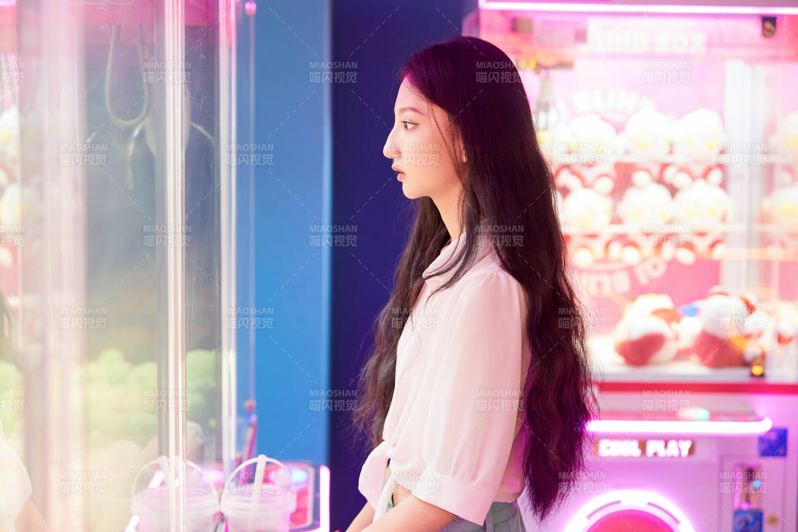 在电子游戏娱乐城玩抓娃娃机的时尚少女图片