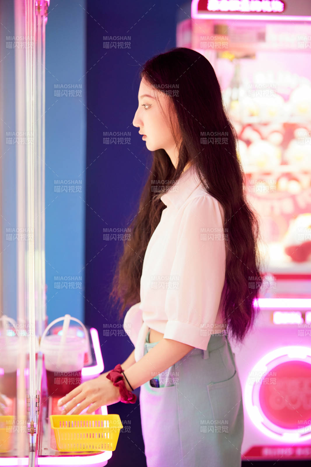 在电子游戏娱乐城玩抓娃娃机的时尚少女图片