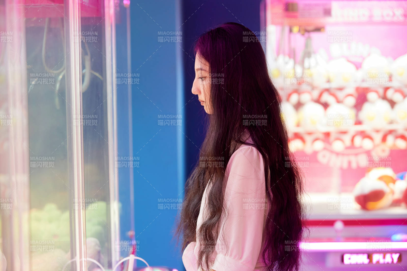 在电子游戏娱乐城玩抓娃娃机的时尚少女图片