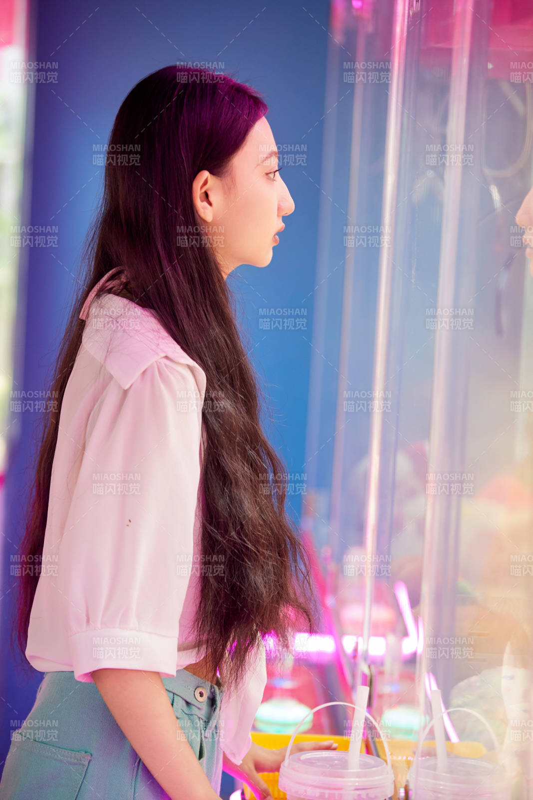 在电子游戏娱乐城玩抓娃娃机的时尚少女图片