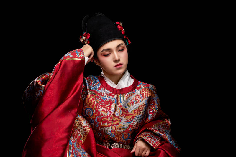 黑色背景下身着明代飞鱼服的青年女性图片