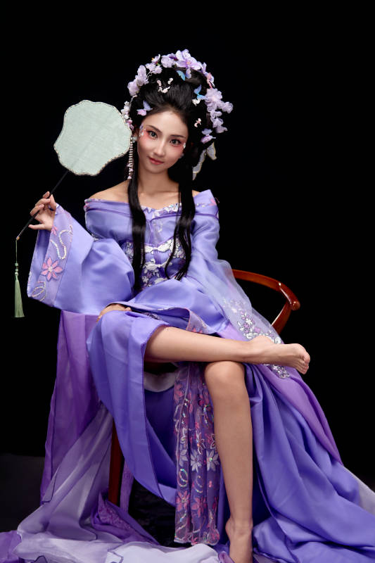 身着簪花仕女装扮坐在木桌上的东方女性图片