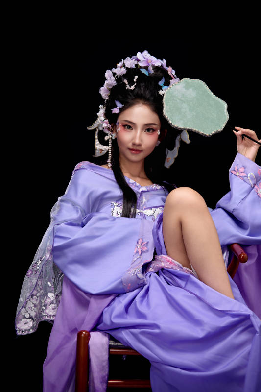 身着簪花仕女装扮坐在木桌上的东方女性图片