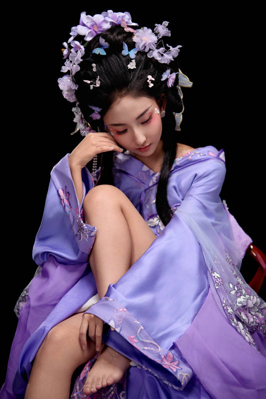 身着簪花仕女装扮坐在木桌上的东方女性图片