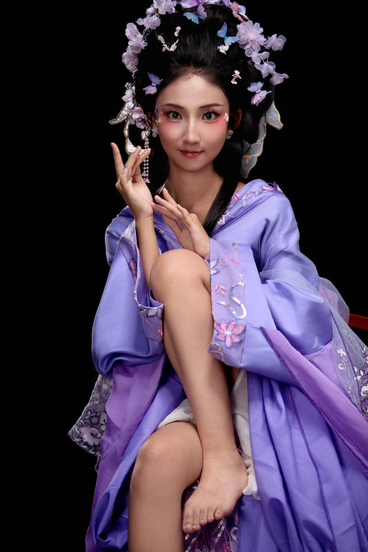 身着簪花仕女装扮坐在木桌上的东方女性图片