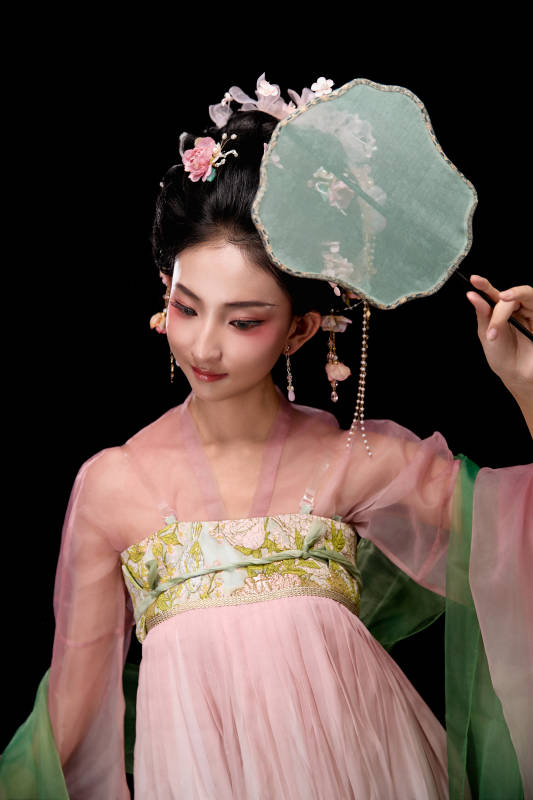 身着唐代宫廷簪花仕女服手持轻扇的女性图片