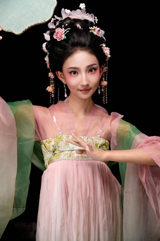 身着唐代宫廷簪花仕女服手持轻扇的女性图片