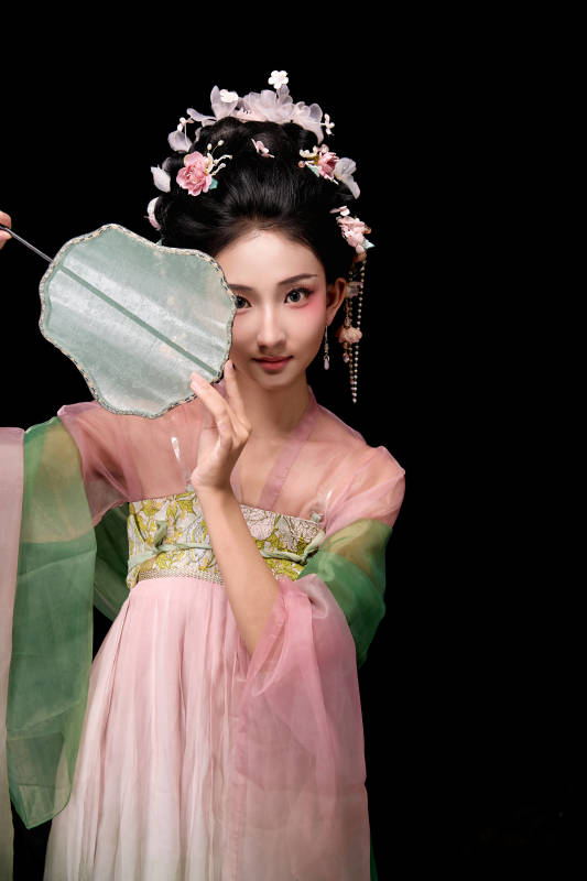 身着唐代宫廷簪花仕女服手持轻扇的女性图片