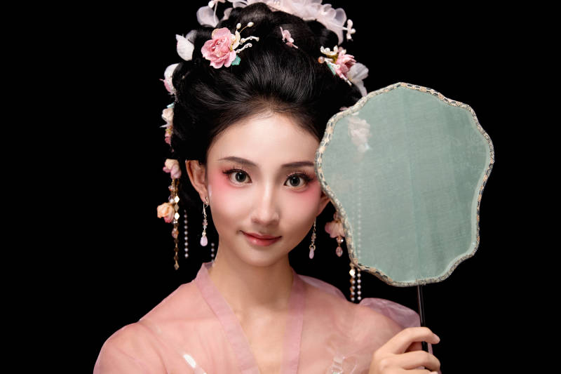 身着唐代宫廷簪花仕女服手持轻扇的女性图片