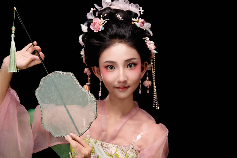 身着唐代宫廷簪花仕女服手持轻扇的女性图片