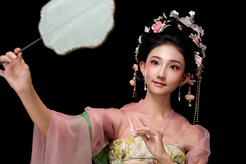 身着唐代宫廷簪花仕女服手持轻扇的女性图片