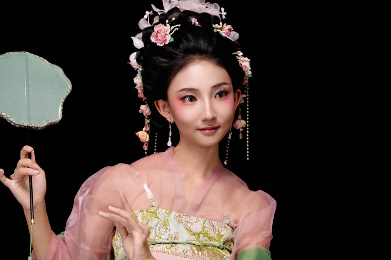 身着唐代宫廷簪花仕女服手持轻扇的女性图片