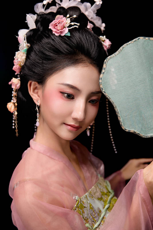 身着唐代宫廷簪花仕女服手持轻扇的女性图片