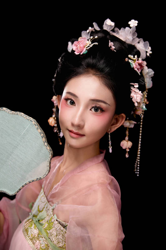 身着唐代宫廷簪花仕女服手持轻扇的女性图片