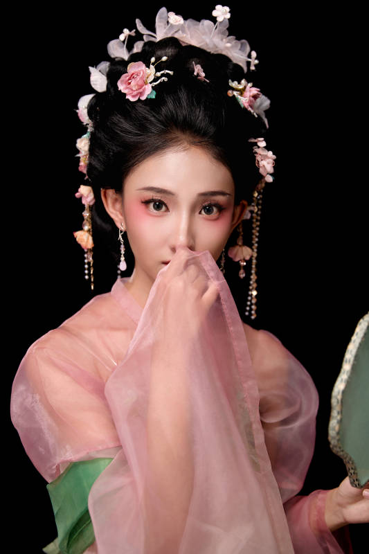 身着唐代宫廷簪花仕女服手持轻扇的女性图片