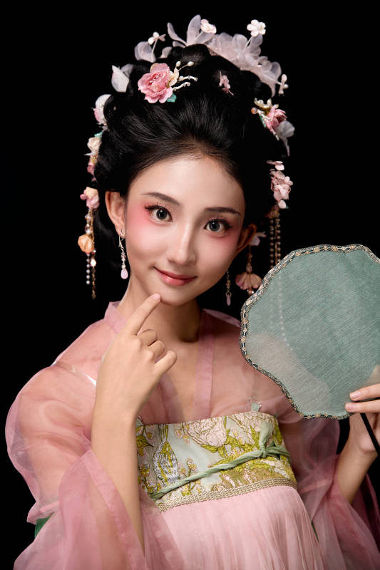 身着唐代宫廷簪花仕女服手持轻扇的女性图片