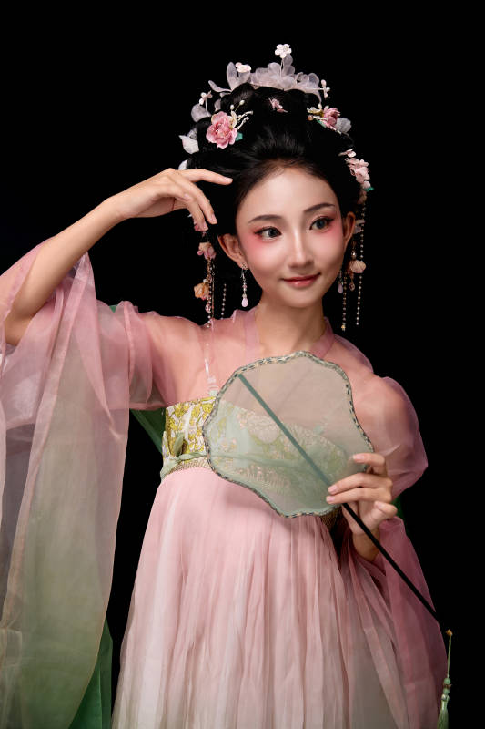 身着唐代宫廷簪花仕女服手持轻扇的女性图片