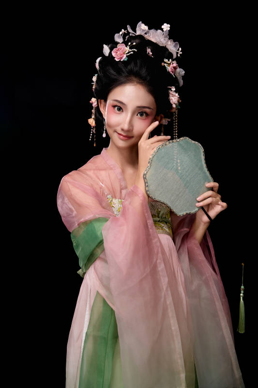 身着唐代宫廷簪花仕女服手持轻扇的女性图片