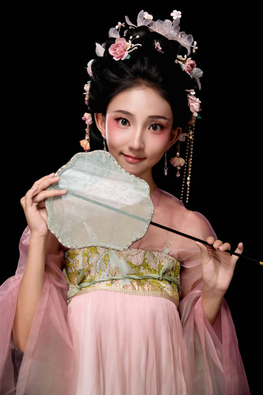 身着唐代宫廷簪花仕女服手持轻扇的女性图片