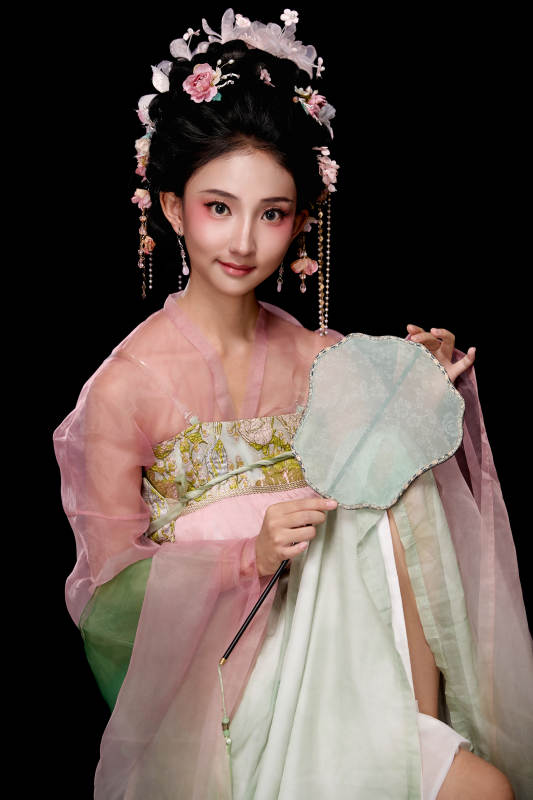 身着唐代簪花仕女服手持轻扇的坐姿女性图片