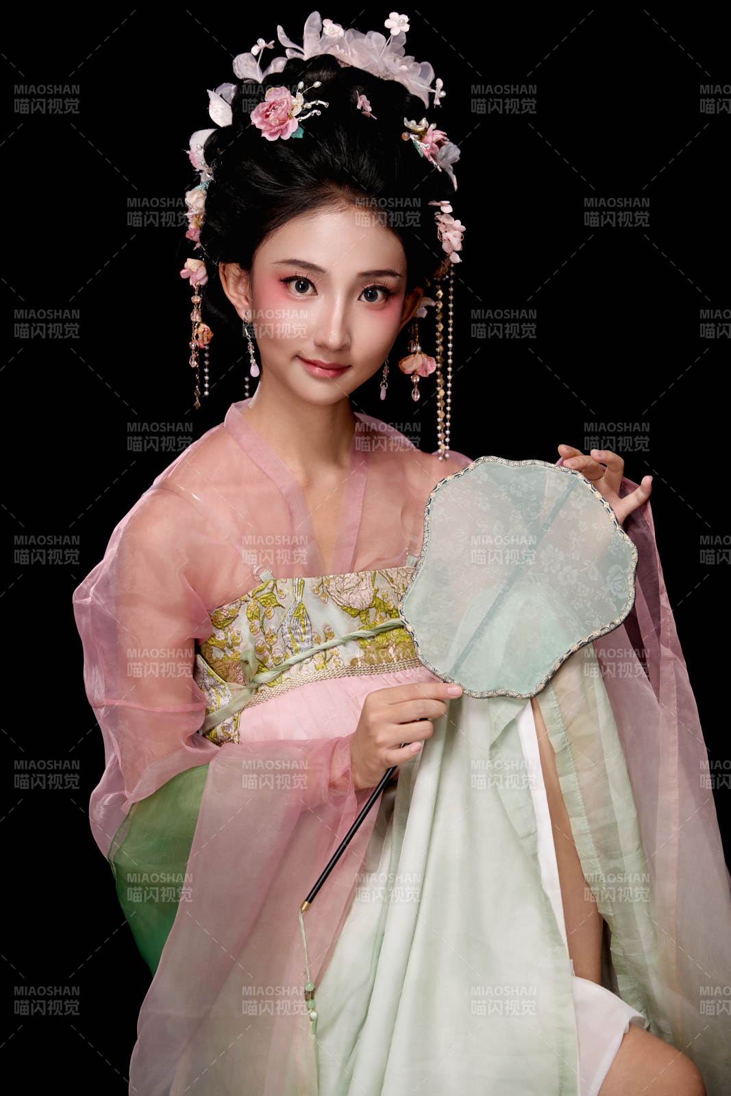 身着唐代簪花仕女服手持轻扇的坐姿女性图片