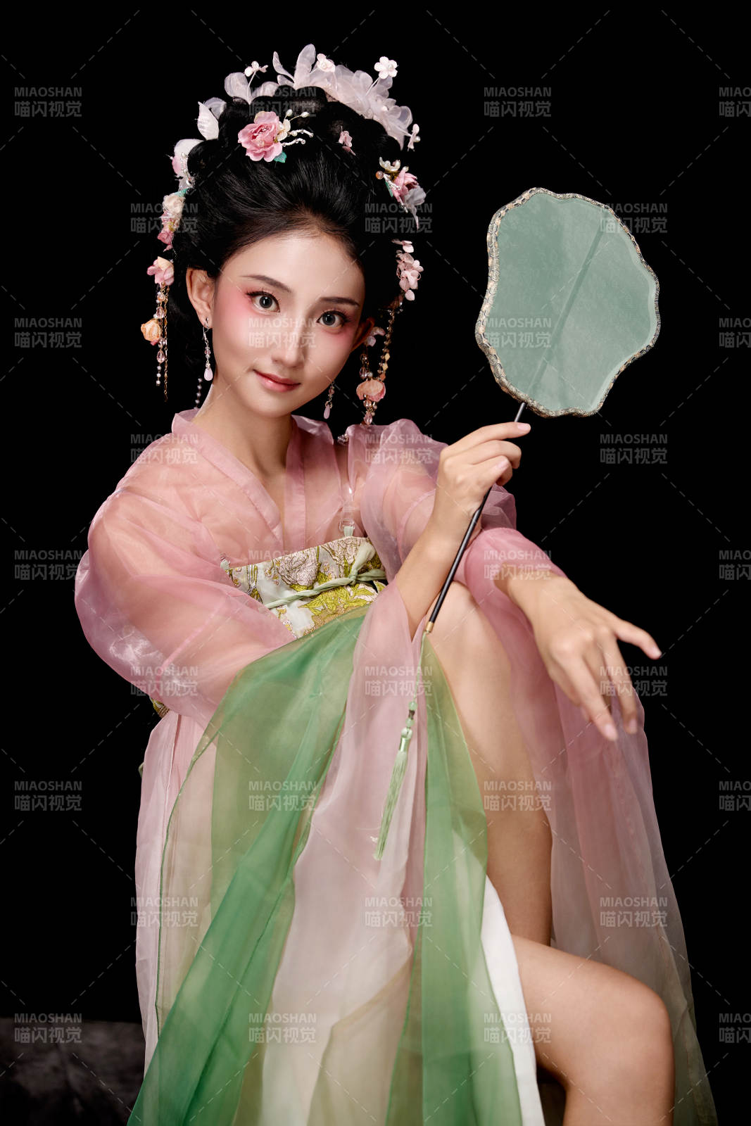 身着唐代簪花仕女服手持轻扇的坐姿女性图片