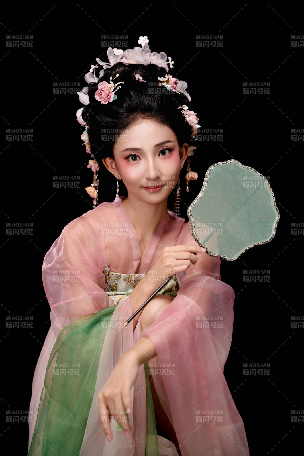 身着唐代簪花仕女服手持轻扇的坐姿女性图片