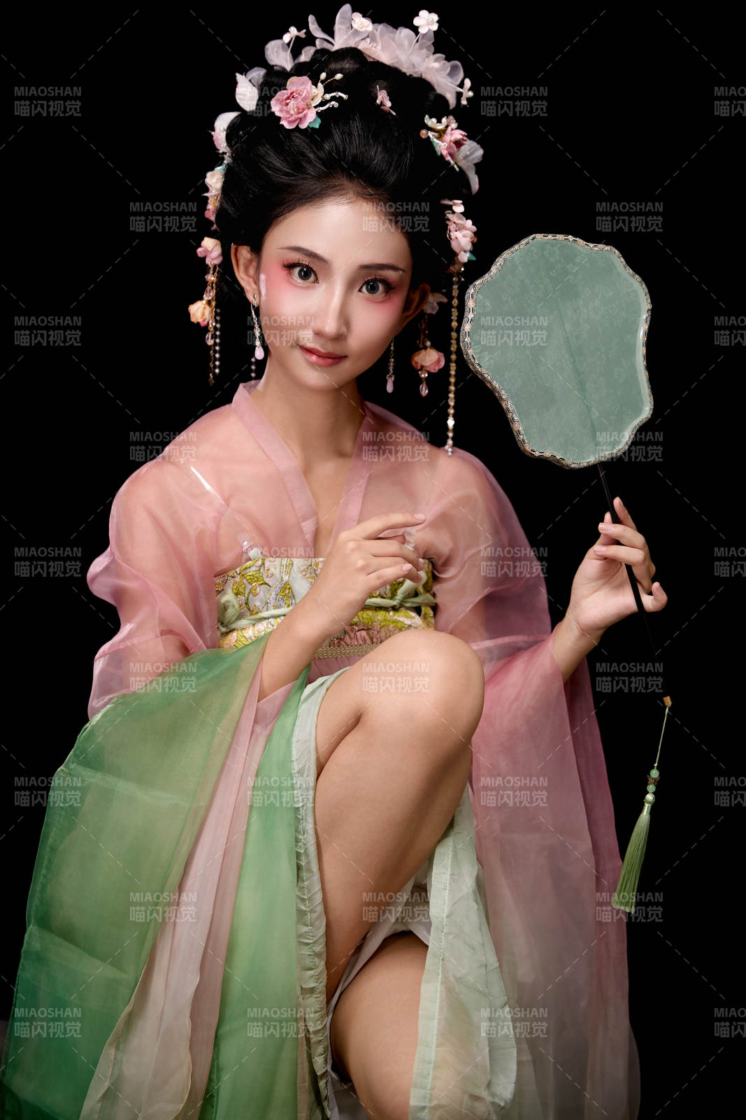 身着唐代簪花仕女服手持轻扇的坐姿女性图片