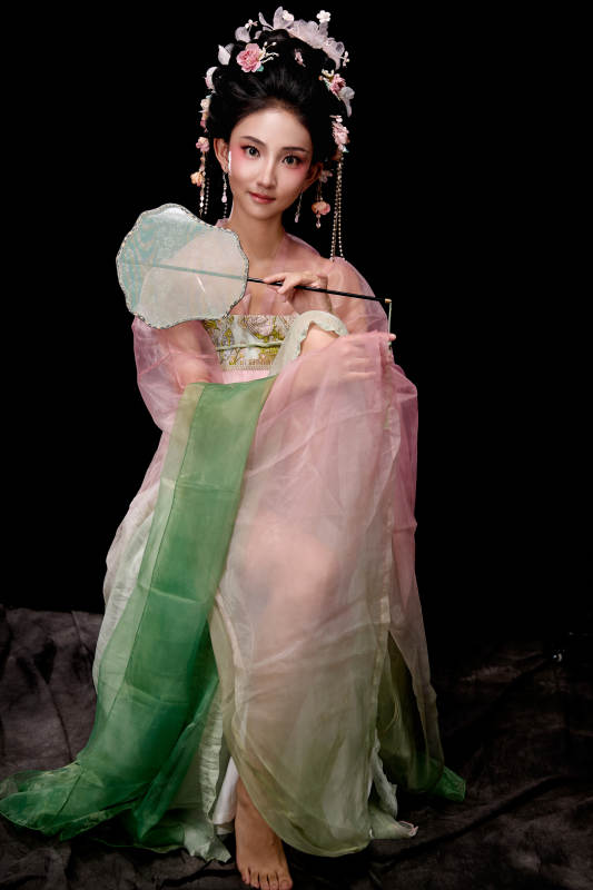 身着唐代簪花仕女服手持轻扇的坐姿女性图片