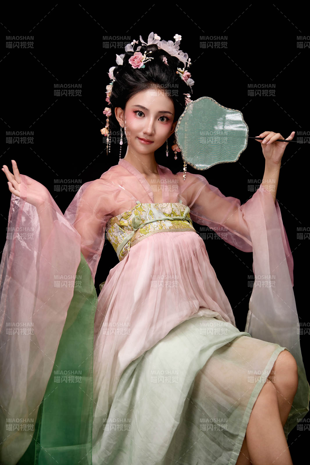 身着唐代簪花仕女服手持轻扇的坐姿女性图片