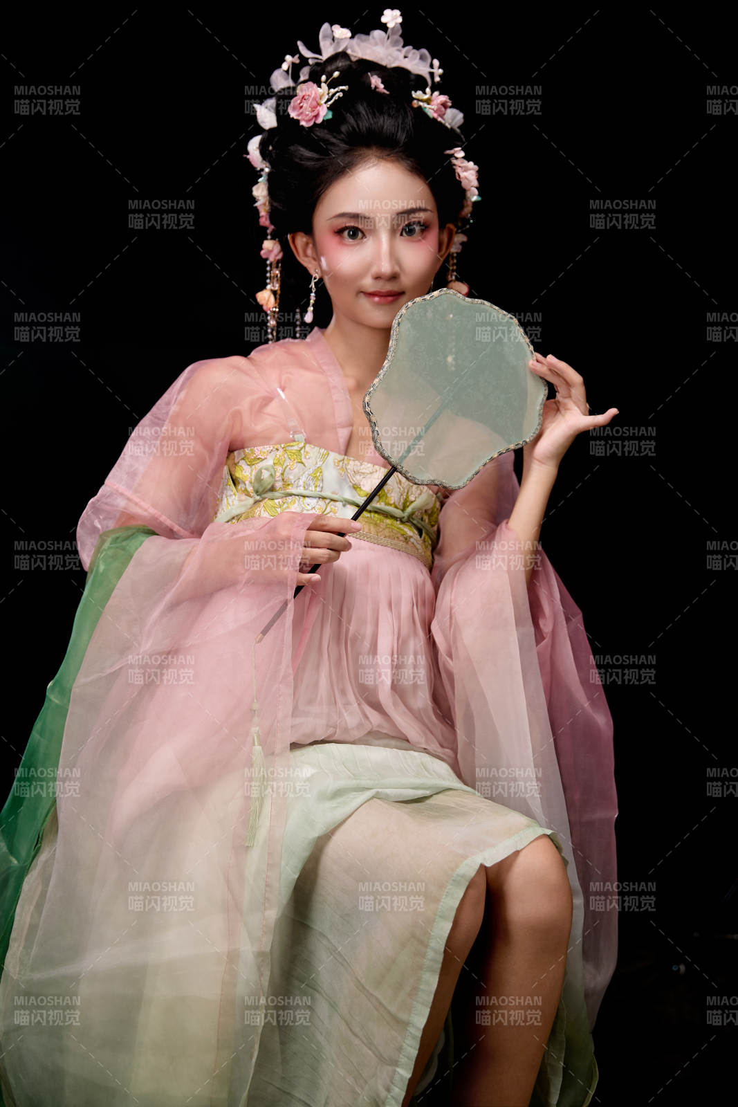 身着唐代簪花仕女服手持轻扇的坐姿女性图片