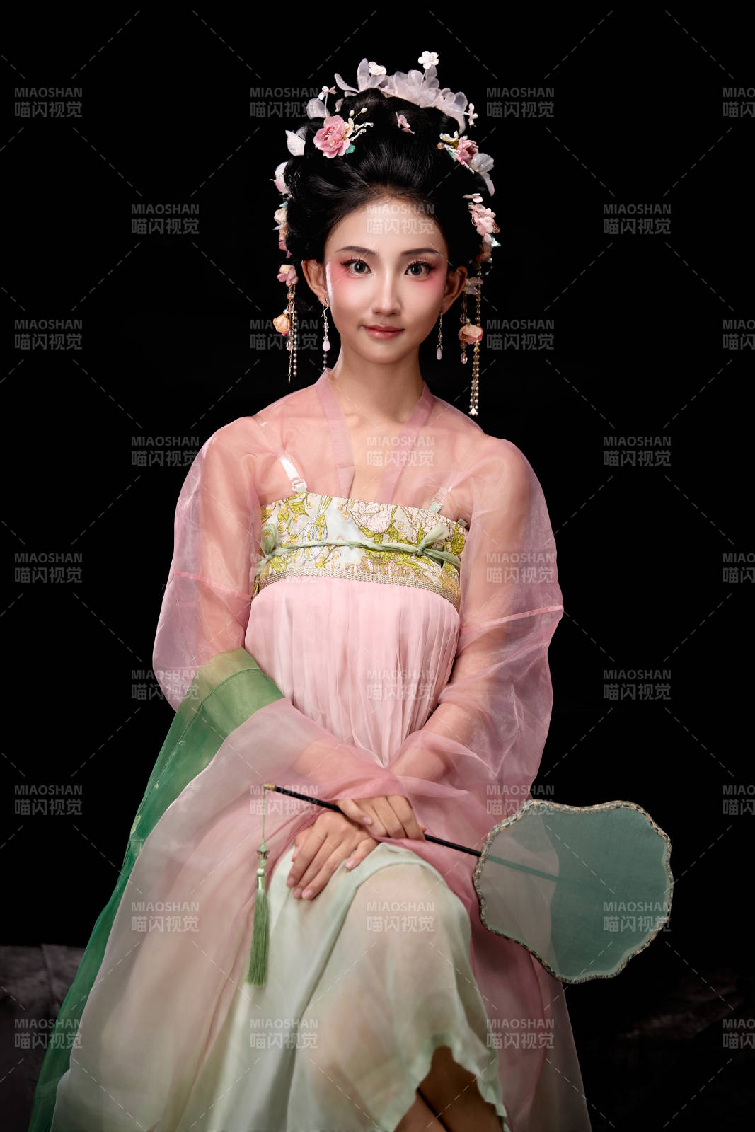 身着唐代簪花仕女服手持轻扇的坐姿女性图片