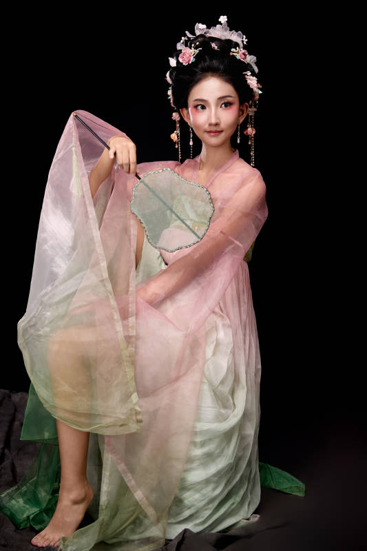 身着唐代簪花仕女服手持轻扇的坐姿女性图片