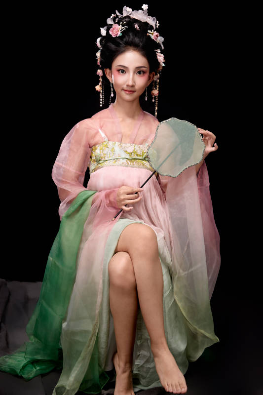 身着唐代簪花仕女服手持轻扇的坐姿女性图片