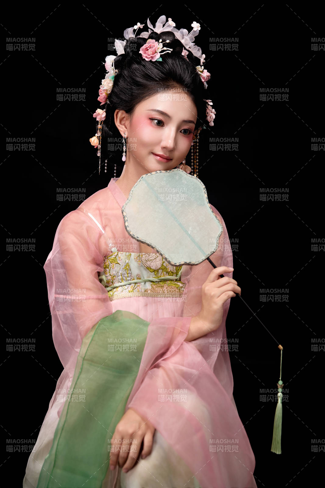 身着唐代簪花仕女服手持轻扇的坐姿女性图片