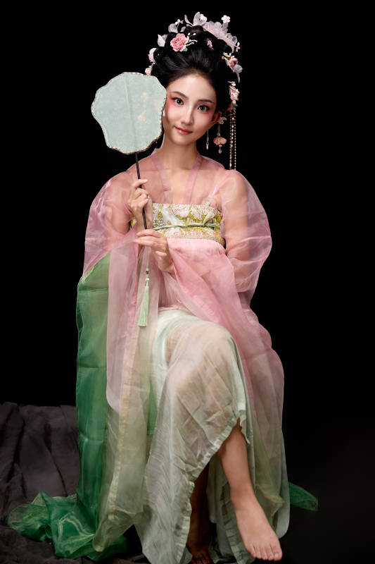 身着唐代簪花仕女服手持轻扇的坐姿女性图片