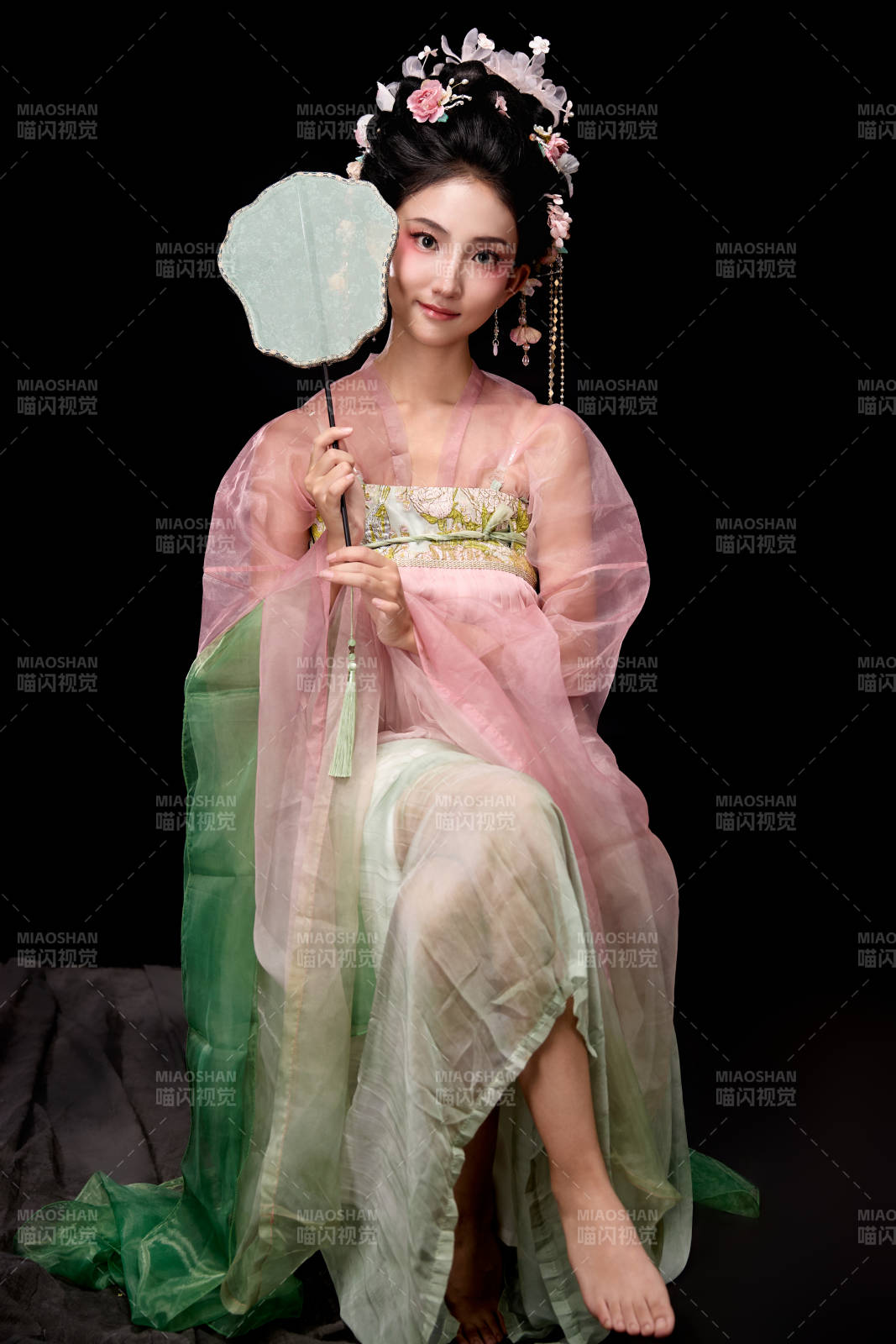 身着唐代簪花仕女服手持轻扇的坐姿女性图片