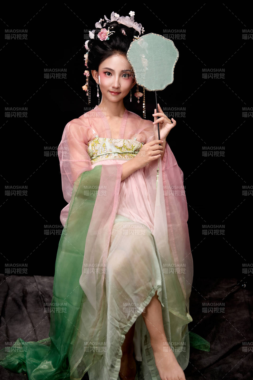 身着唐代簪花仕女服手持轻扇的坐姿女性图片