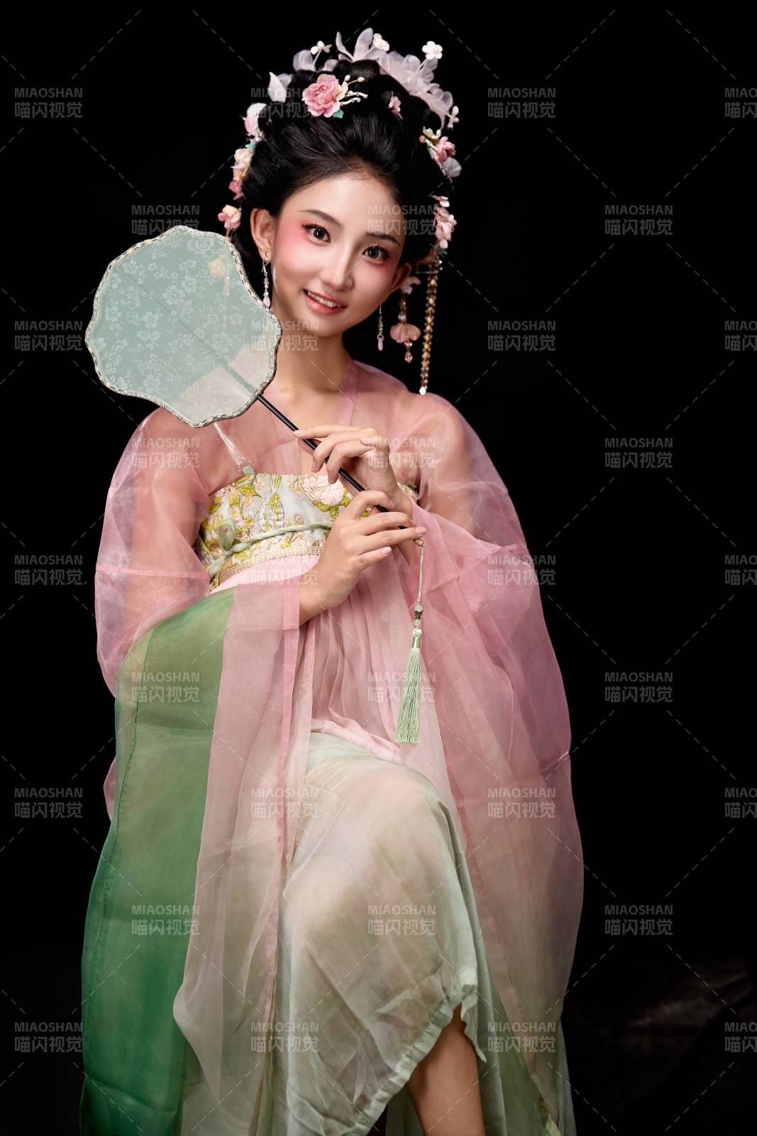 身着唐代簪花仕女服手持轻扇的坐姿女性图片