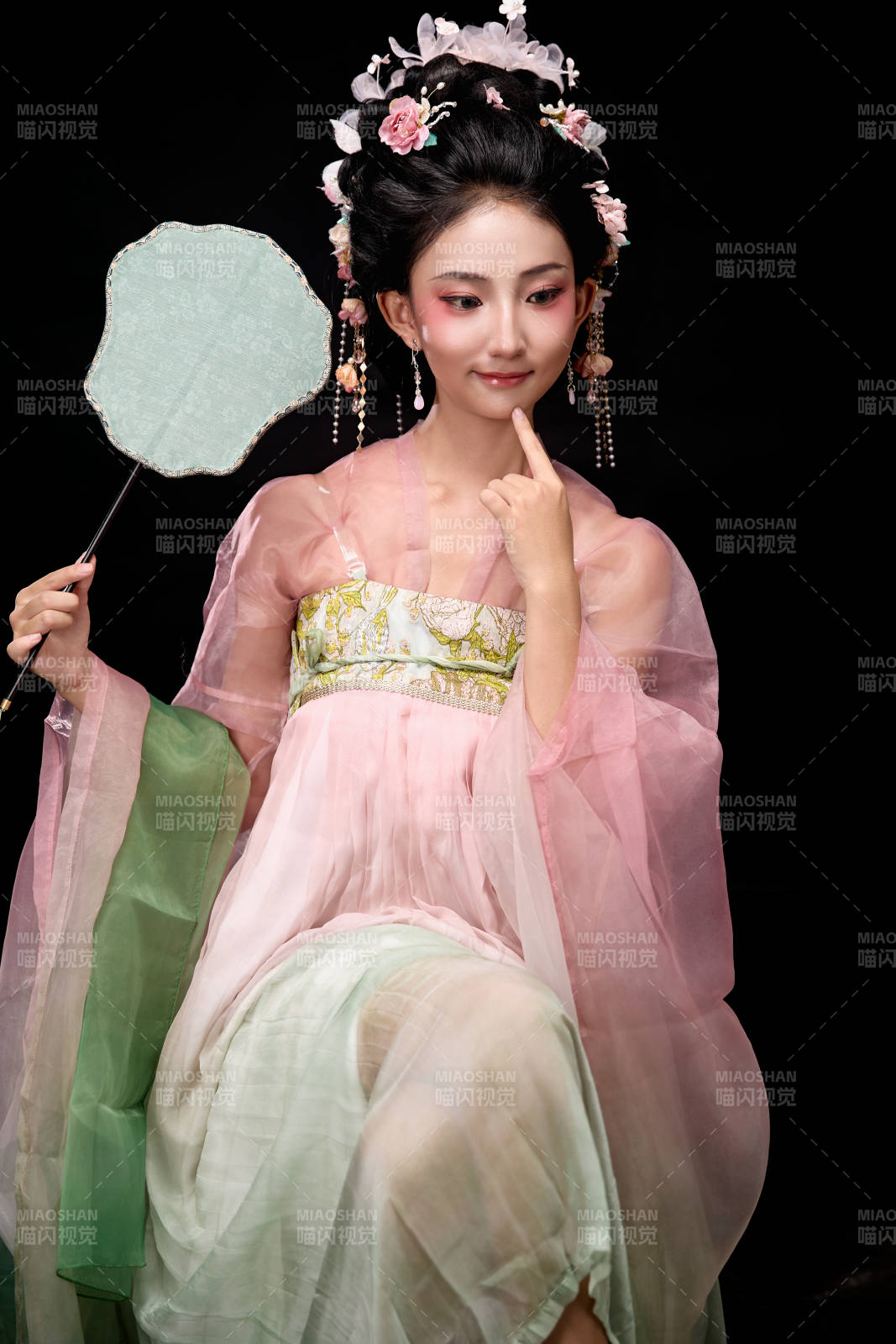 身着唐代簪花仕女服手持轻扇的坐姿女性图片