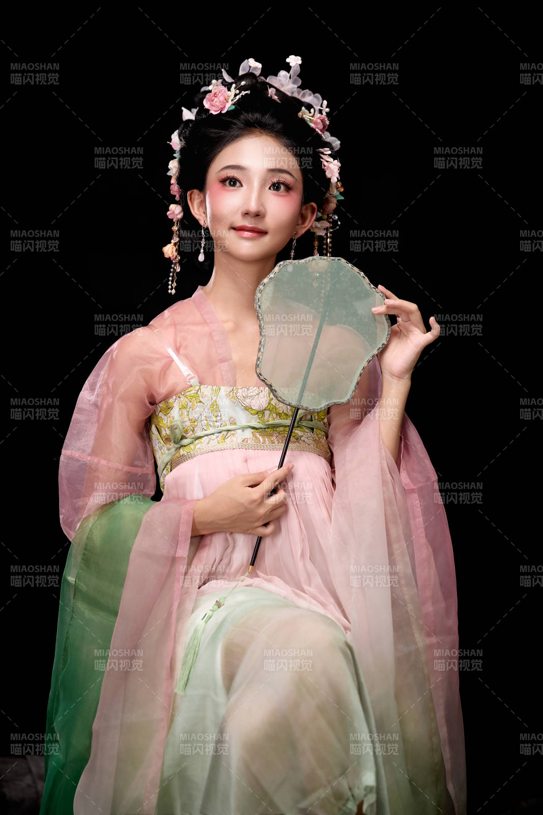 身着唐代簪花仕女服手持轻扇的坐姿女性图片