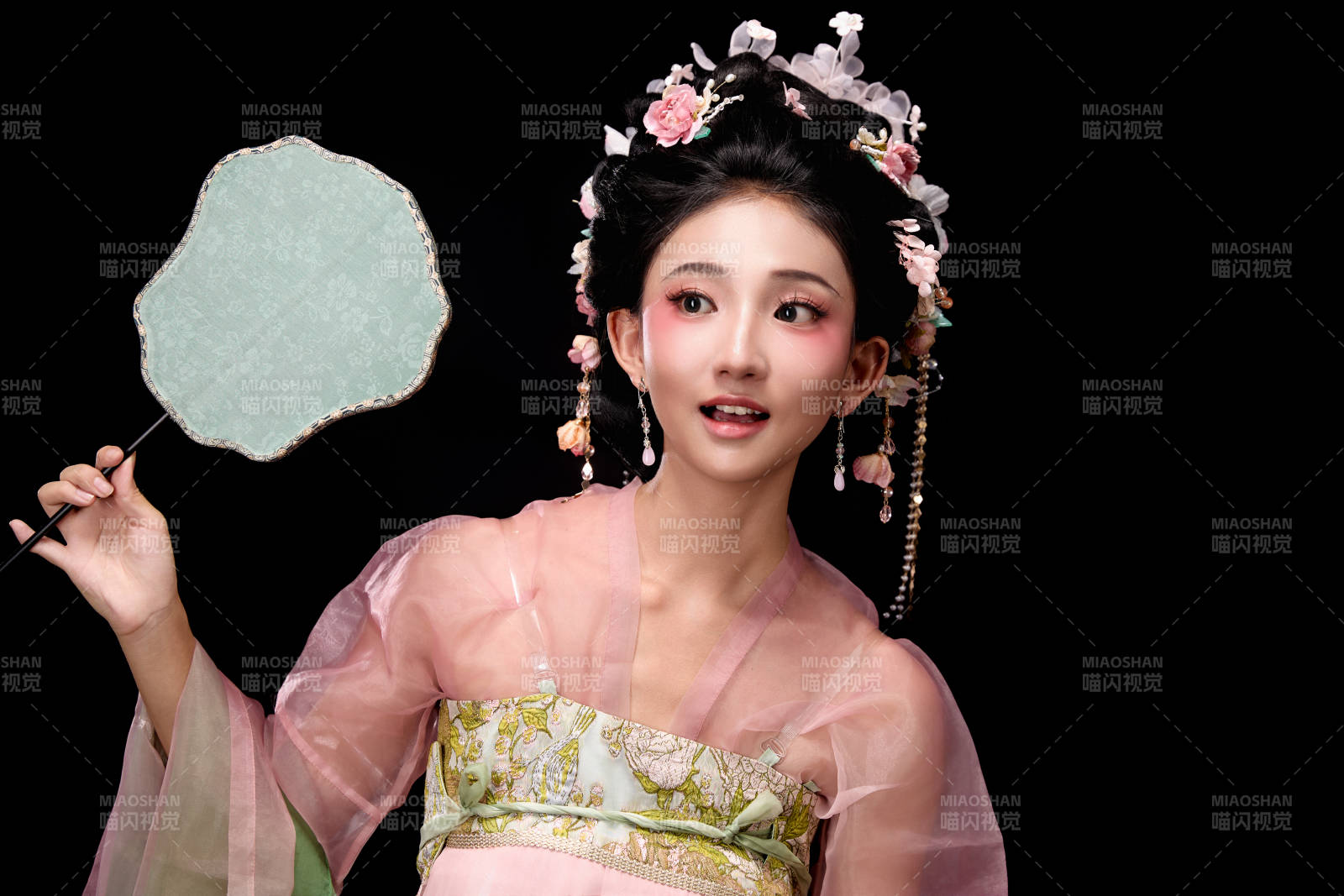 身着唐代簪花仕女服手持轻扇的坐姿女性图片