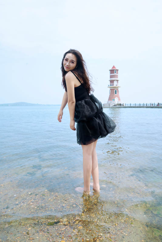 在草原湖畔戏水游玩拍照的亚洲美女图片