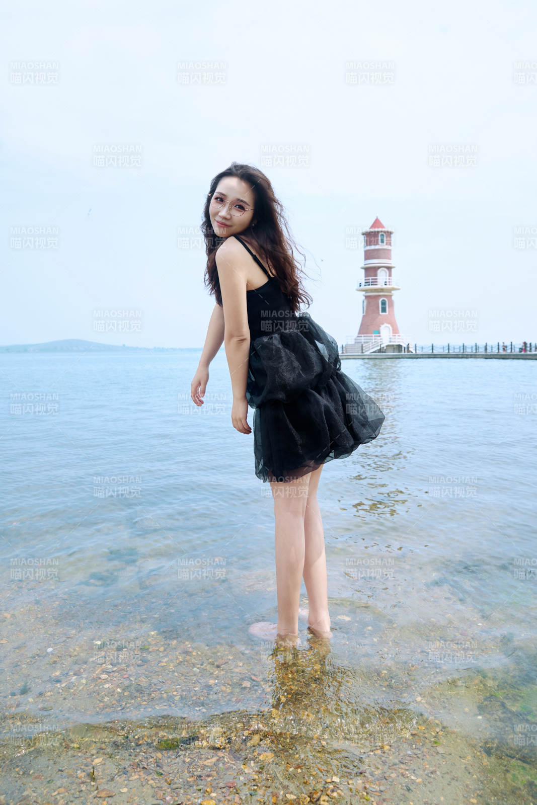 在草原湖畔戏水游玩拍照的亚洲美女图片